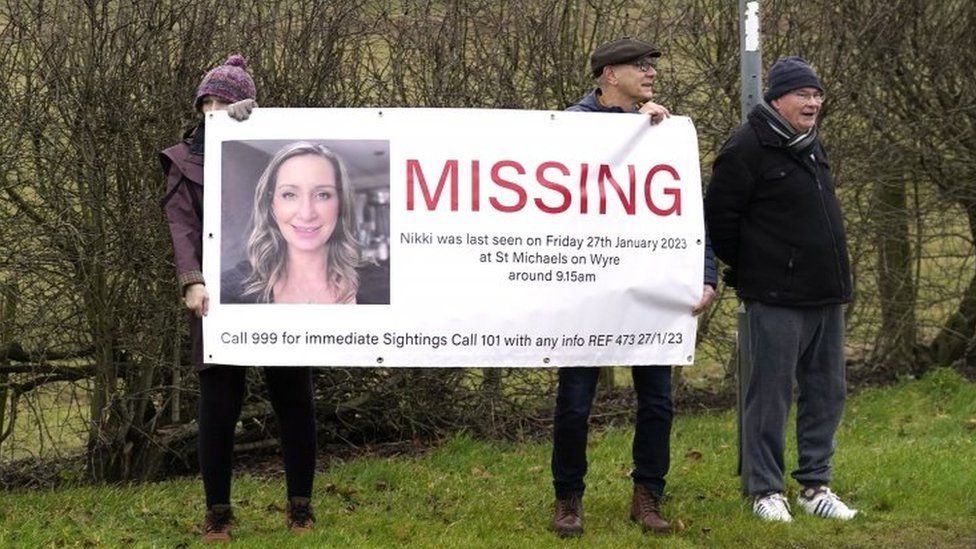 Members of the public line the road into St Michael"s on Wyre, Lancashire, with missing posters of Nicola Bulley