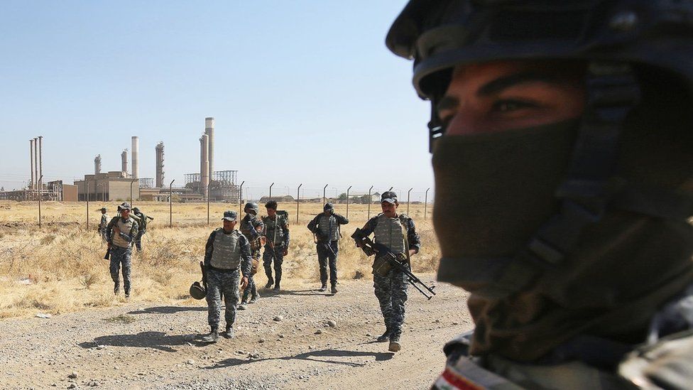 Iraqi forces walk in front of an oil production plant as they head towards the city of Kirkuk during an operation against Kurdish fighters on October 16, 2017