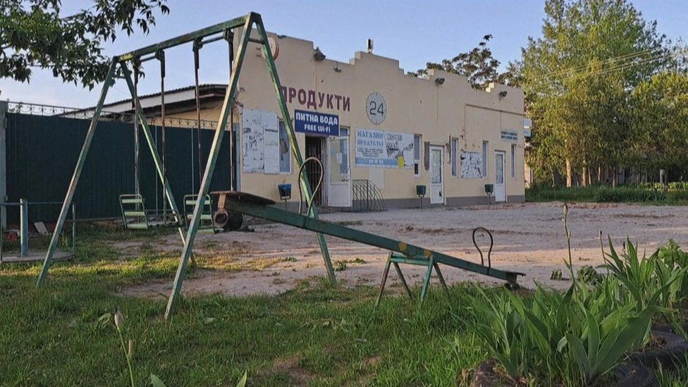 Damaged shop in Zelenivka, with a children's play area in front