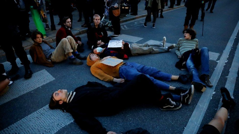 Люди лежат на земле во время акции протеста против введения чрезвычайного положения на польской границе с Беларусью