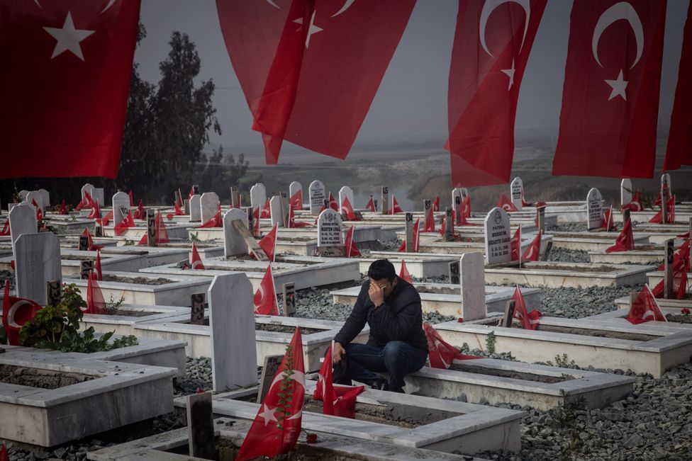 A man mourns at the grave of a loved one that was killed in last year's earthquake at a cemetery on February 06, 2024 in Hatay, Turkey.
