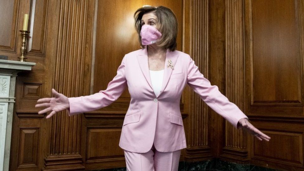 Nancy Pelosi wears a mask that matches her pink suit