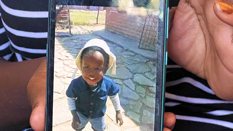Тетя Кекетсо Сауле показывает фотографию своего племянника на своем мобильном телефоне