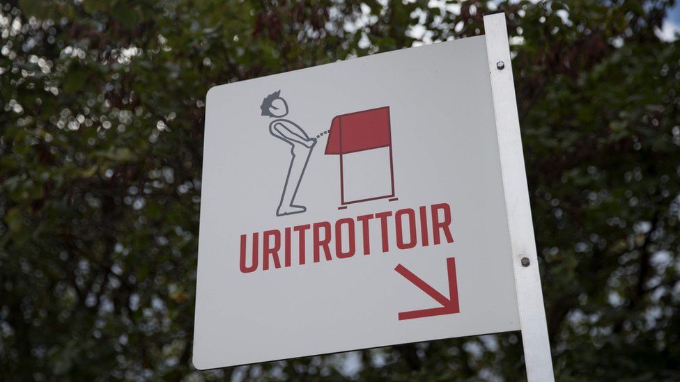 A picture shows a sign indicating a "uritrottoir" public urinal on August 13, 2018