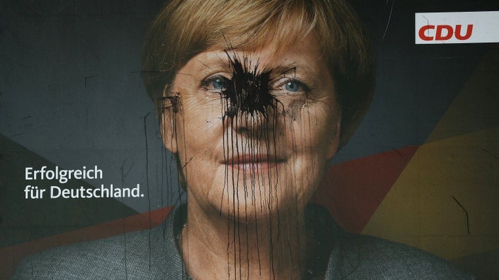 Large poster of Angela Merkel has been covered in black splash of paint over her face