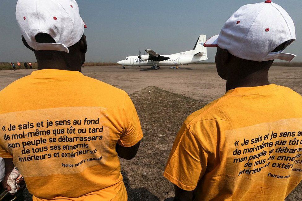 An excerpt from the last letter to his wife written in captivity by slain Congolese independence leader Patrice Lumumba is seen printed on T-shirts worn by members of the public in Tshumbe, Democratic Republic of Congo, on 22 June, as the airplane carrying Lumumba's family lands.