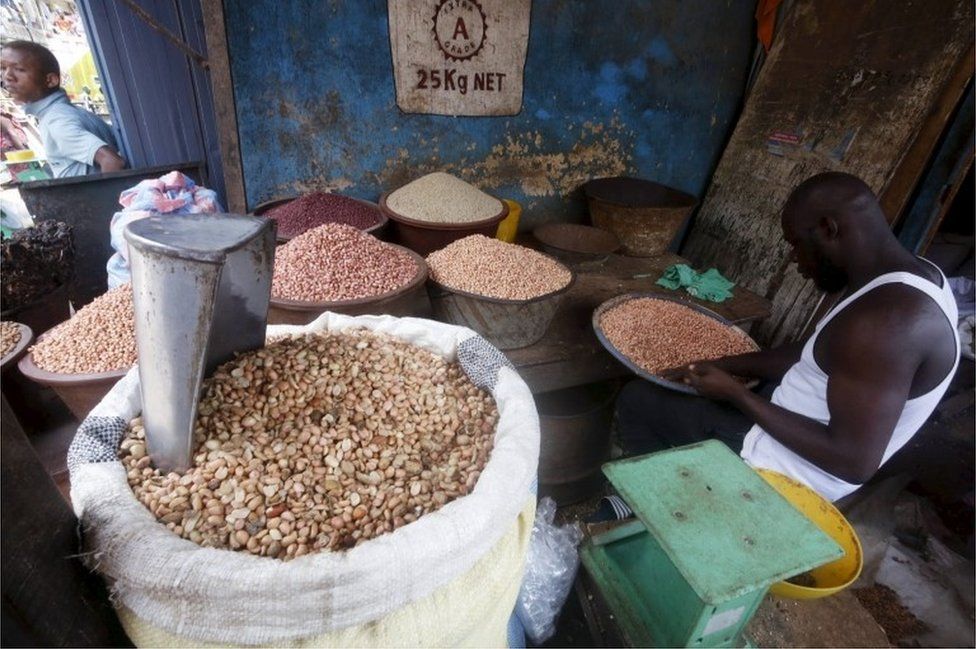 A man works on groundnut seeds inside his store at Adjame's market in Abidjan, Ivory Coast, October 2, 2015