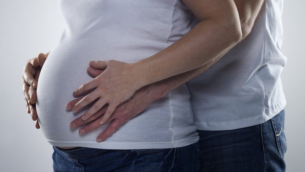Pregnant woman held by partner