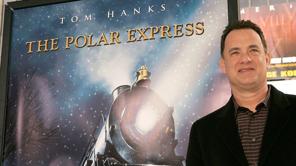 Tom Hanks in front of poster for The Polar Express
