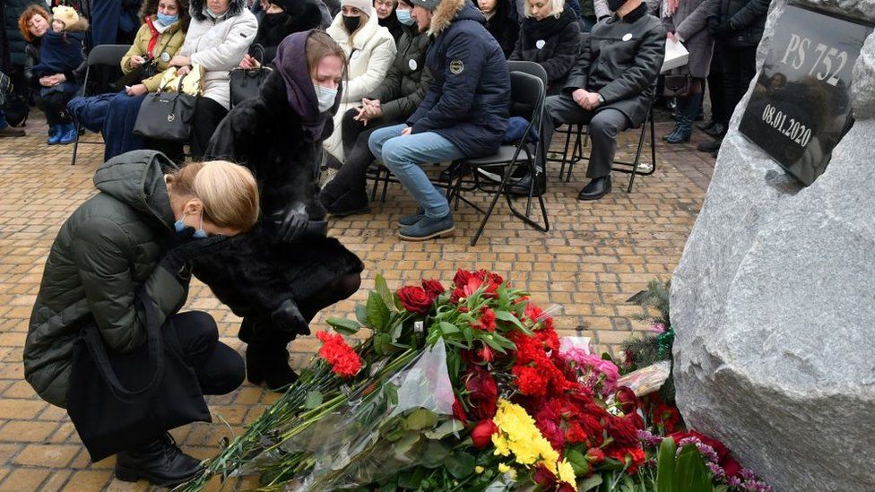 Women lay flowers at a memorial ceremony for victims of the Ukraine air crash (08/01/21)