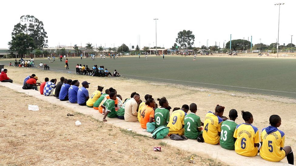 Girls watch and play football in Zambia