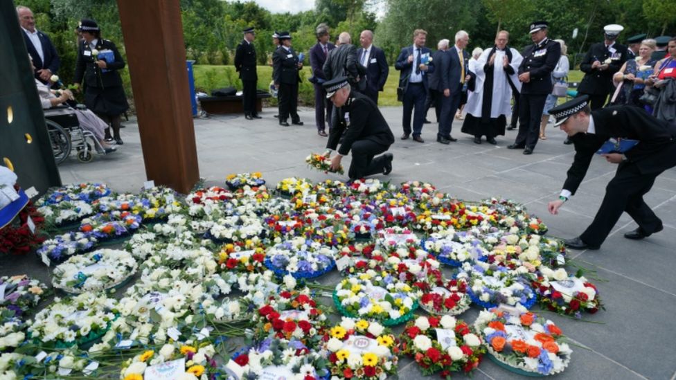 Police officers lay flowers at the unveiling of the UK Police Memorial