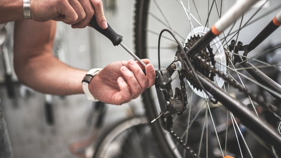 Close up shot on male hands inside bicycle store while repairing the gearshift on rear wheel of a mountain bike.