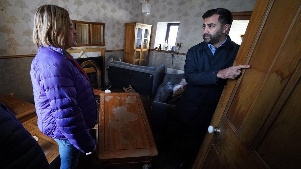 First Minister Humza Yousaf (right) speaks to Paul Fowlie and partner Kim Clark as he looks at water damage in their house during a visit to Brechin, Scotland