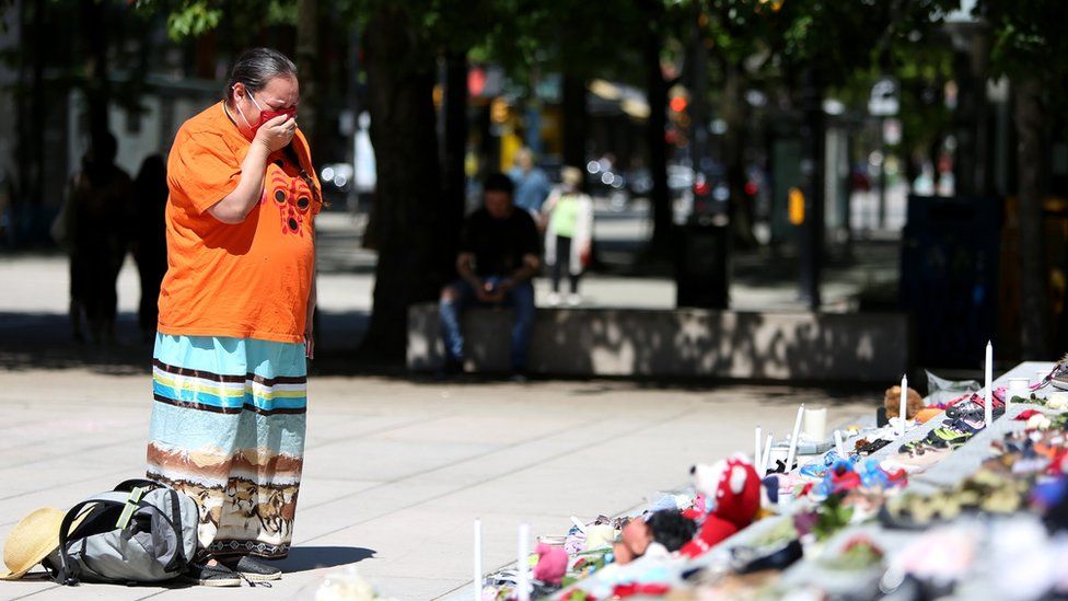 A woman mourns over 215 pairs of children's shoes outside Vancouver Art Gallery.