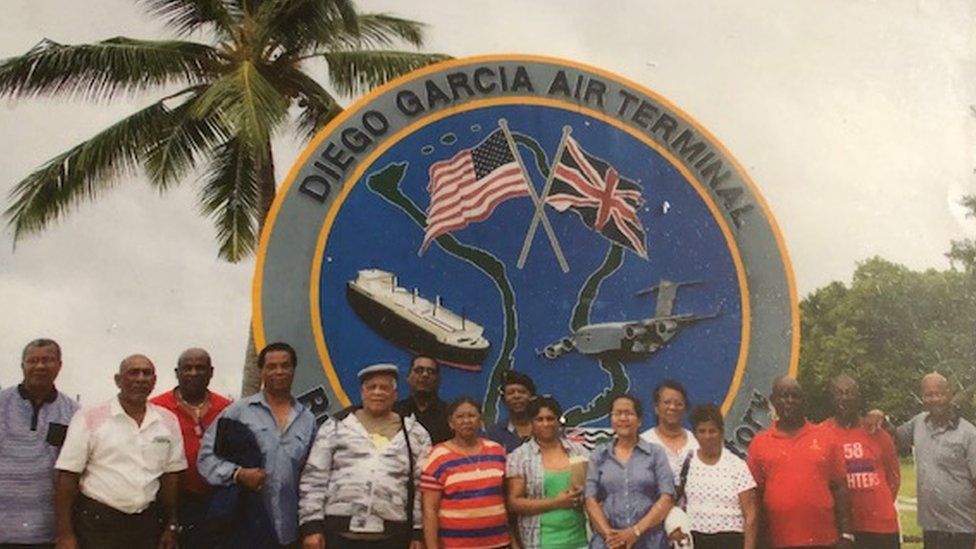 First generation Chagossian exiles standing in front of the military airbase on Diego Garcia