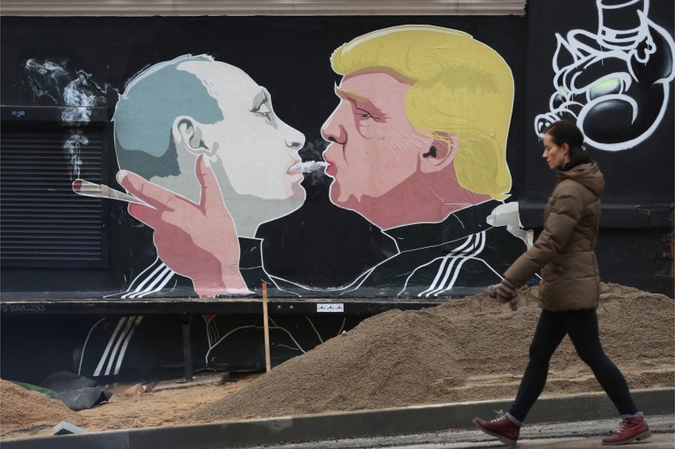 A woman walks past a mural showing US president-elect Donald Trump (right) blowing marijuana smoke into the mouth of Russian President Vladimir Putin on the wall of a restaurant on November 23, 2016 in Vilnius, Lithuania.