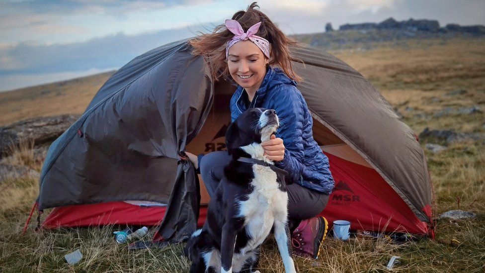 Rebecca strokes her dog whilst wild camping in Dartmoor