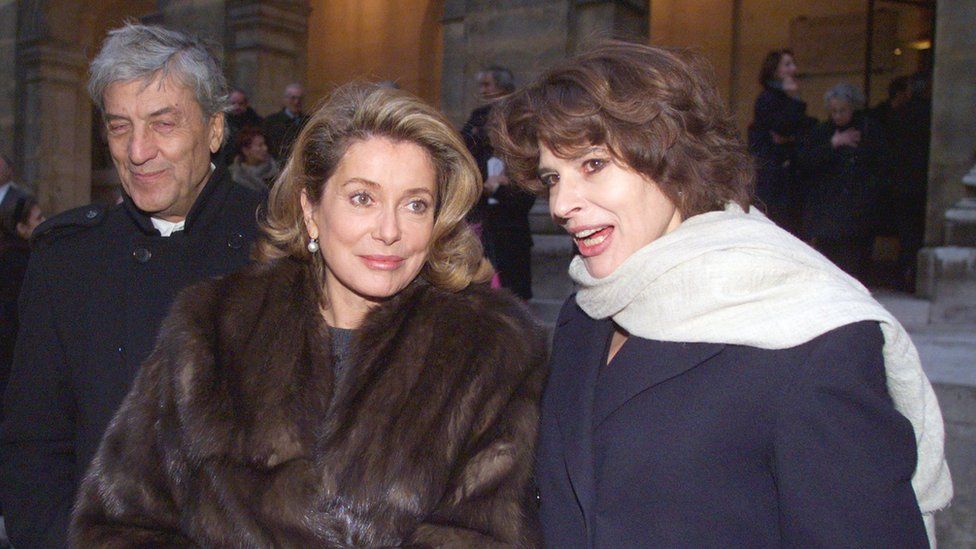 फ्रांसीसी अभिनेत्रियाँ कैथरीन डेनेउवे (सी) और फैनी अर्दंत और इतालवी फैशन डिजाइनर नीनो सेरुति (जी) ने 15 दिसंबर, 1999 को पेरिस में ललित कला अकादमी छोड़ दी।