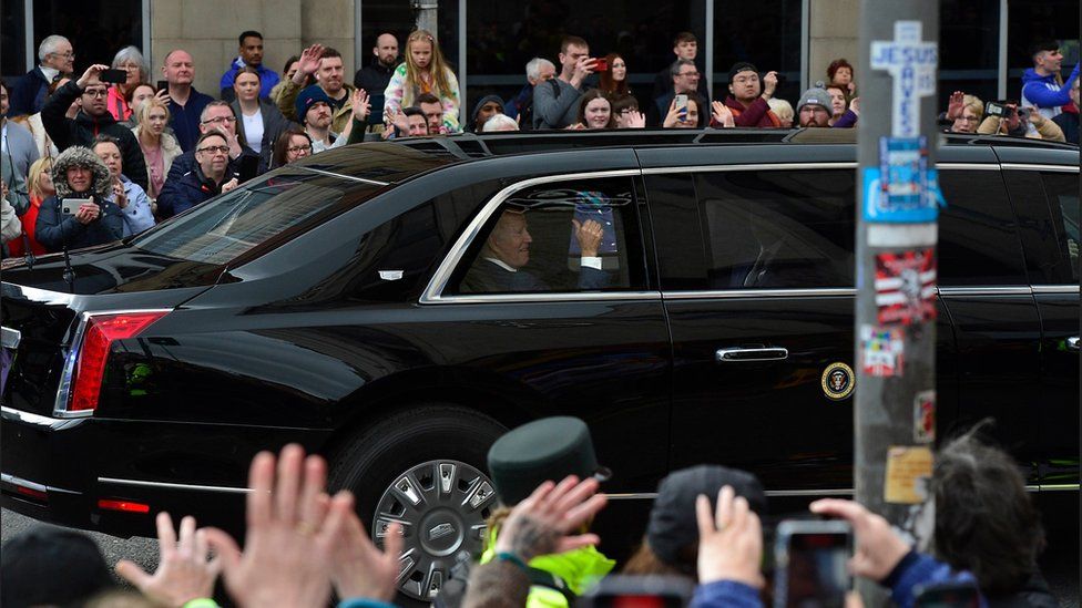 Joe Biden gives onlookers the thumbs-up as he passes them in his presidential car