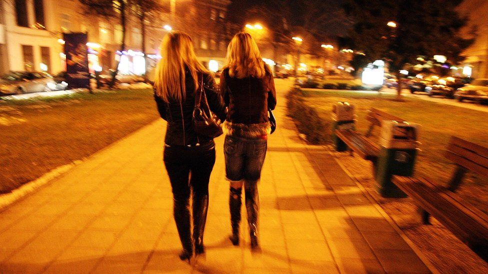 Unidentified young prostitutes walking down a street