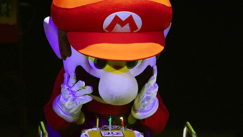 Super Mario' blows out the candles on a cake during celebrations and a live performance of the most well-known Mario music to mark the game's 30th anniversary i