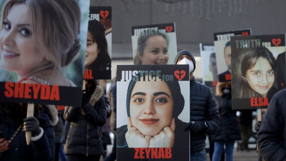 People hold signs with images of the victims of the downed flight in Toronto, Ontario, Canada, on 8 January 2021