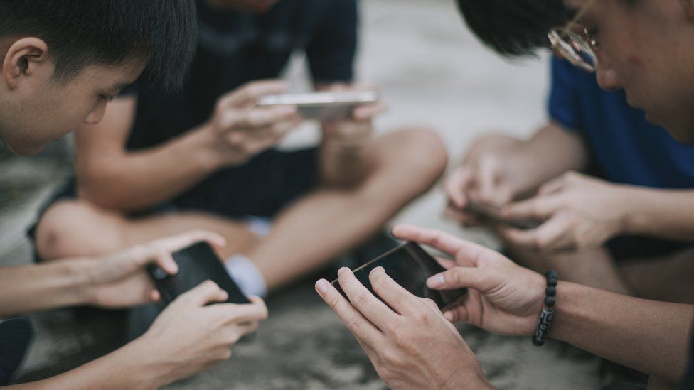 A group of teenage Chinese boys playing mobile video game.