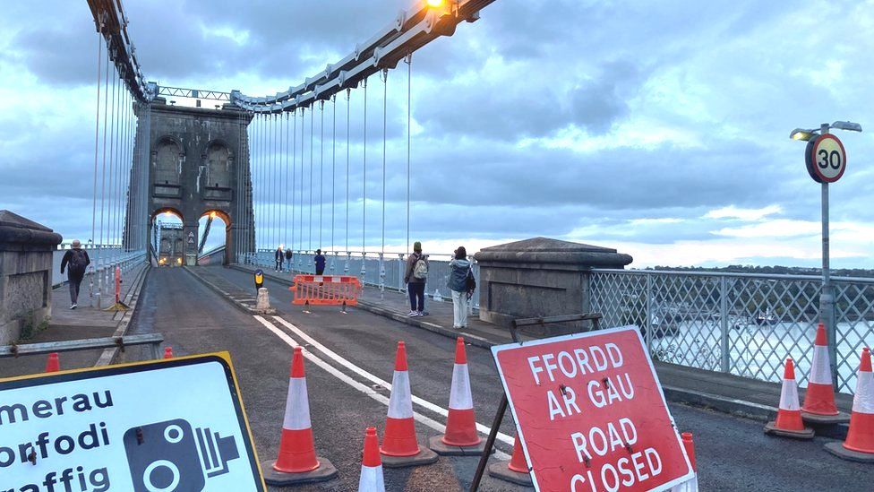 Menai Bridge with pedestrians walking across and closure signage