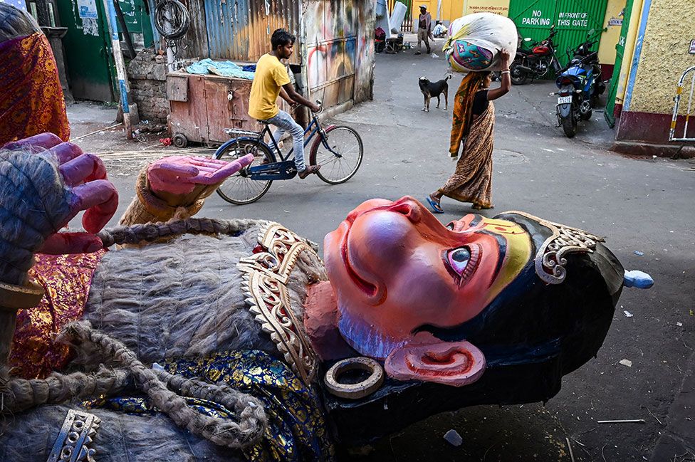 Commuters walk past a partially finished statue of Hindu god Lord Hanuman, Kolkata, India, on 5 April 2023