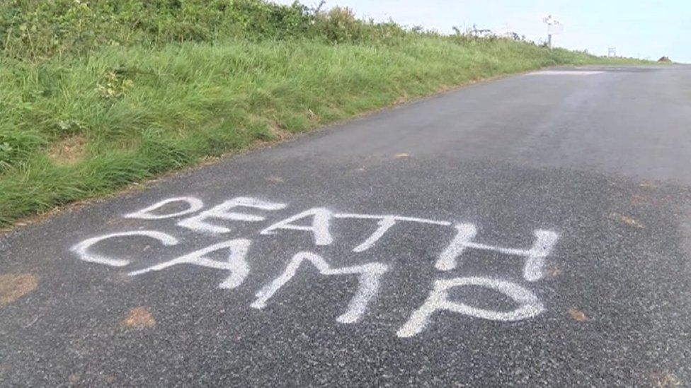 The words "death camp" spray painted on a road