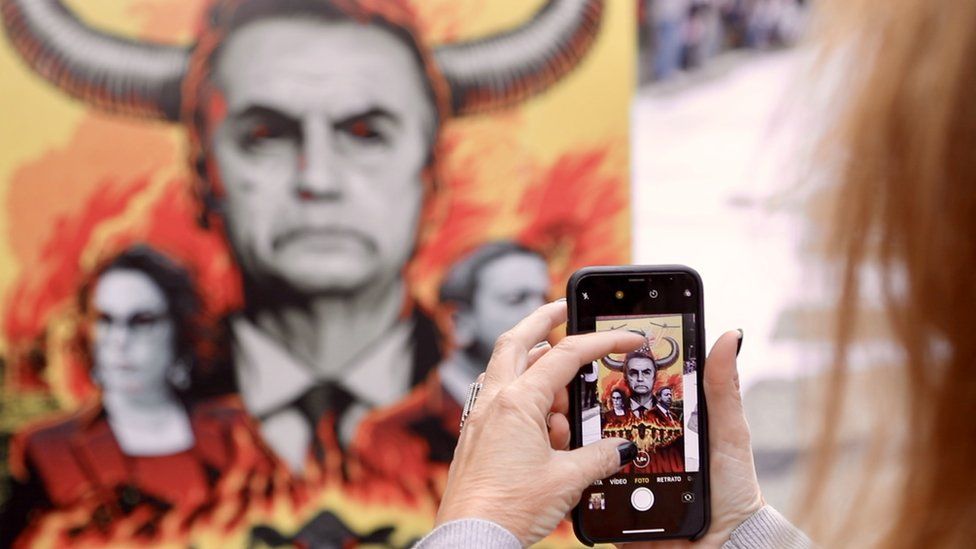 Protester takes picture of image depicting President Bolsonaro