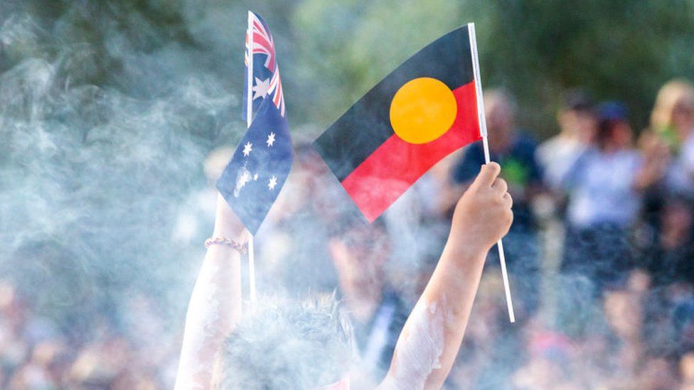An Indigenous and Australian flag are both raised during a ceremony in Sydney