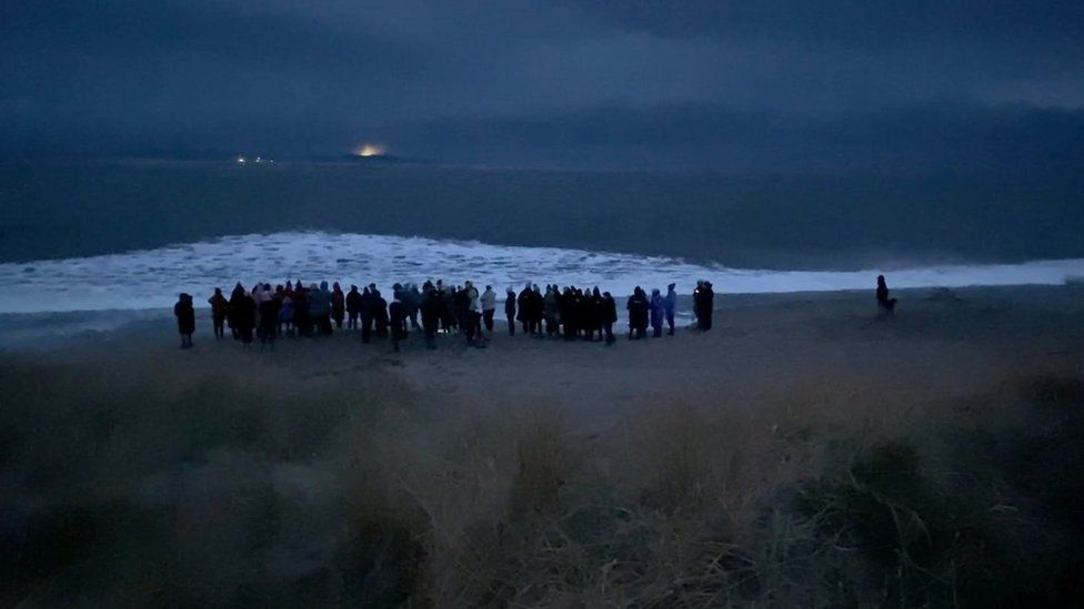 Family and friends of Deirdre McShane lay roses in the sea during a vigil