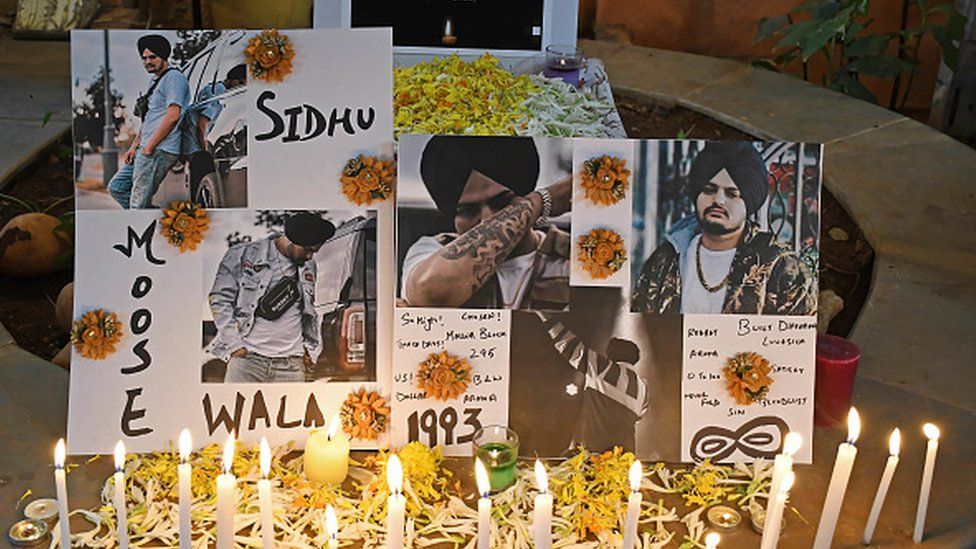A poster with photos of late Indian singer Shubhdeep Singh Sidhu, known by his stage name Sidhu Moose Wala is seen at a candle light vigil in Mumbai.