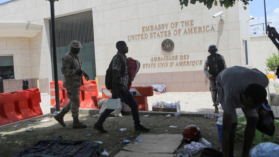 Мужчина несет свои вещи возле посольства США