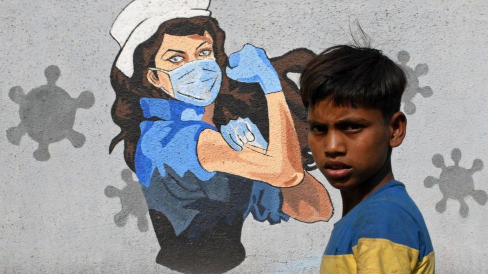 Мальчик проходит мимо граффити, нарисованного, чтобы привлечь внимание к проблеме коронавируса.