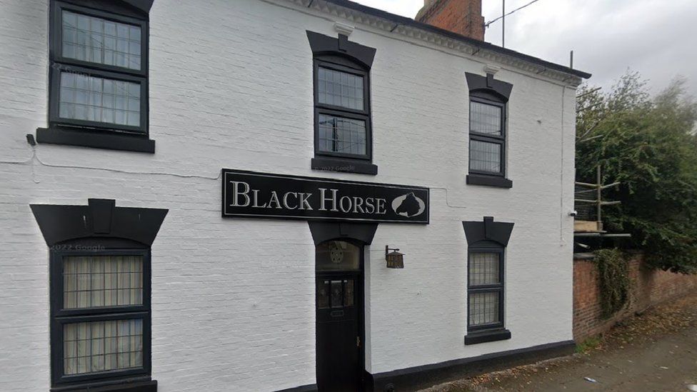 A pub painted black and white with the name 'Black Horse' over the door