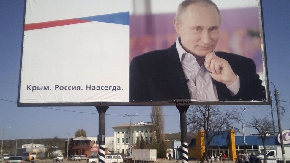 A billboard with a portrait of Russian President Vladimir Putin is displayed on a street in Kerch, Crimea, April 016. The board reads: "Crimea. Russia. Forever."