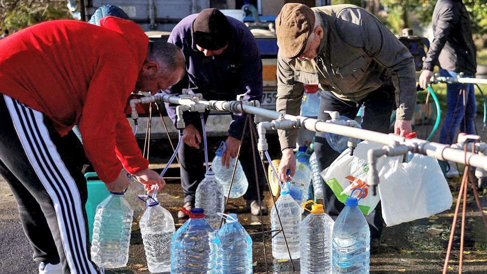 Local people fill up bottles with fresh drinking water in Mykolaiv
