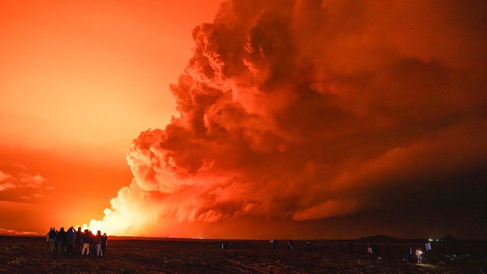 People gather to watch as molten lava flows out from a fissure on the Reykjanes peninsula, 16 March