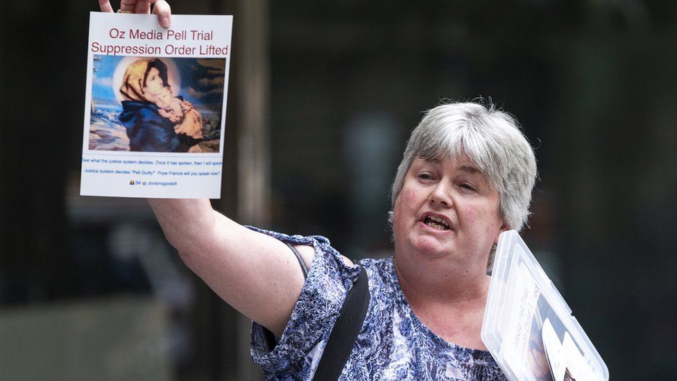 A woman protests outside George Pell's court hearing on Tuesday holding up a sign which reads "Oz Media Pell Trial Suppression Order Lifted"