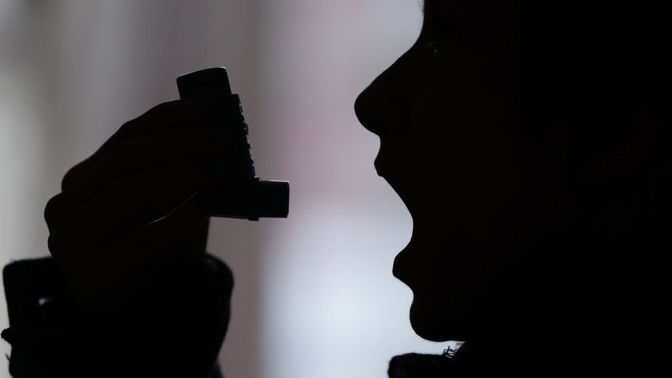 Person using an asthma inhaler in profile