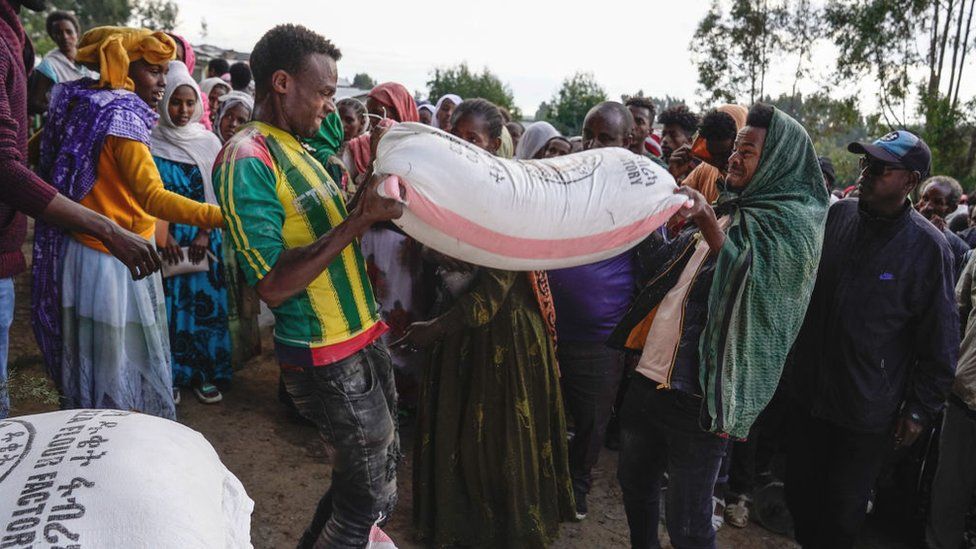 Volunteers lift bags of food aid at a displaced people's camp in Debark in Amhara, Ethiopia - October 2021
