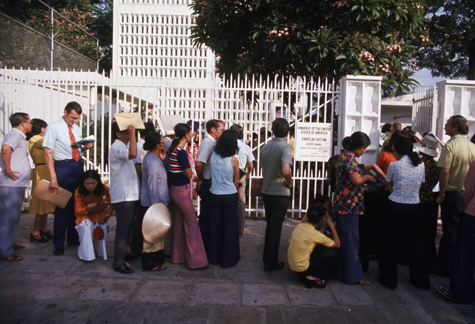 Americans and dependents wait outside of the U.S. Embassy for busses to go to Tan Son Nhut Airbase for evacuation.
