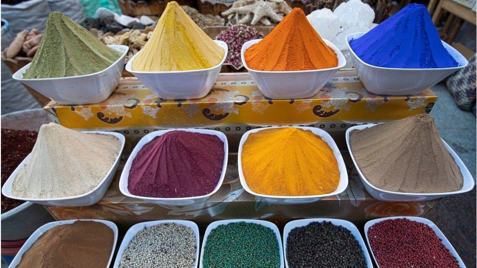 Multi-coloured spices on display in white bowls.