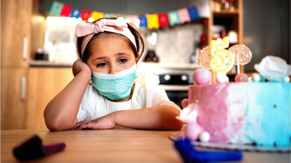 Child with birthday cake and face covering