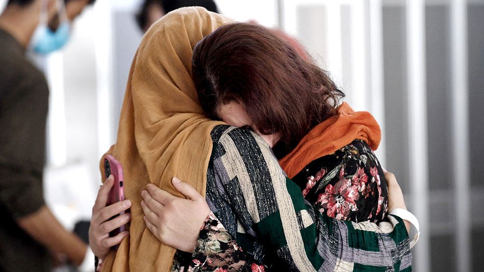 A woman embraces her sister-in-law as she arrives with other Afghan refugees