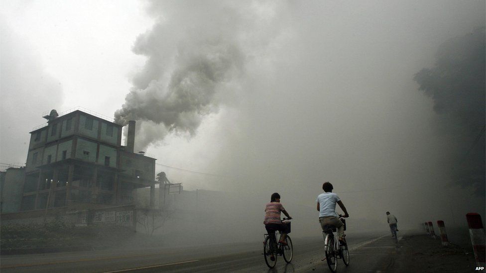 This picture shows cyclists passing through thick pollution from a factory in Beijing, China