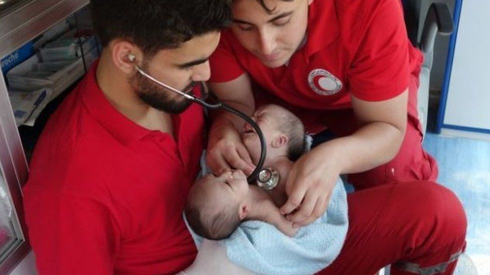 Red Crescent workers examine the babies